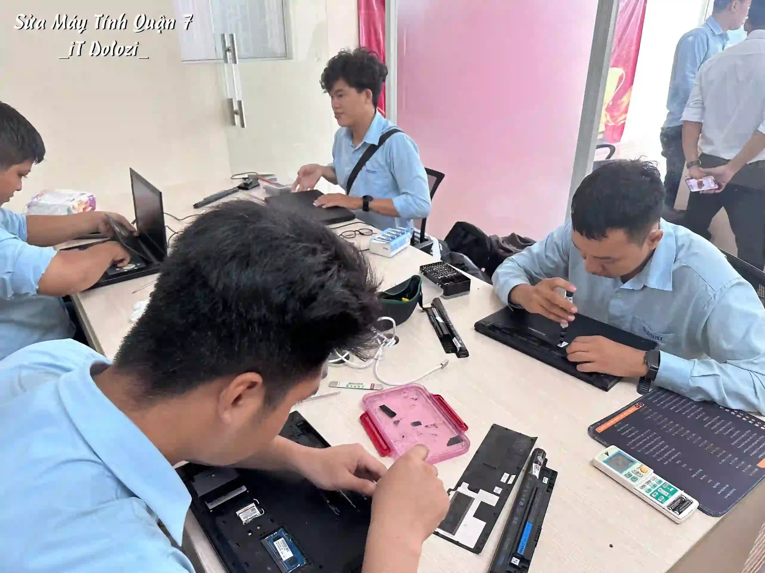 Các kỹ thuật viên đang sửa máy tính và laptop cho khách hàng